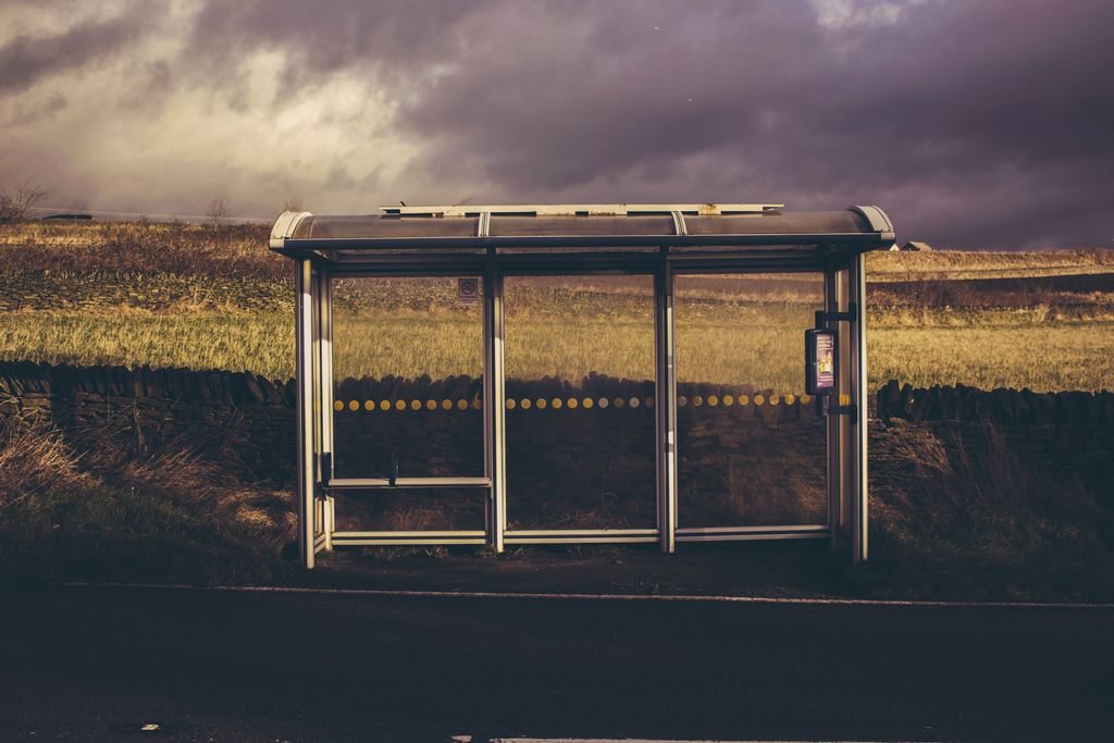 Gray and black waiting shed under cloudy sky.